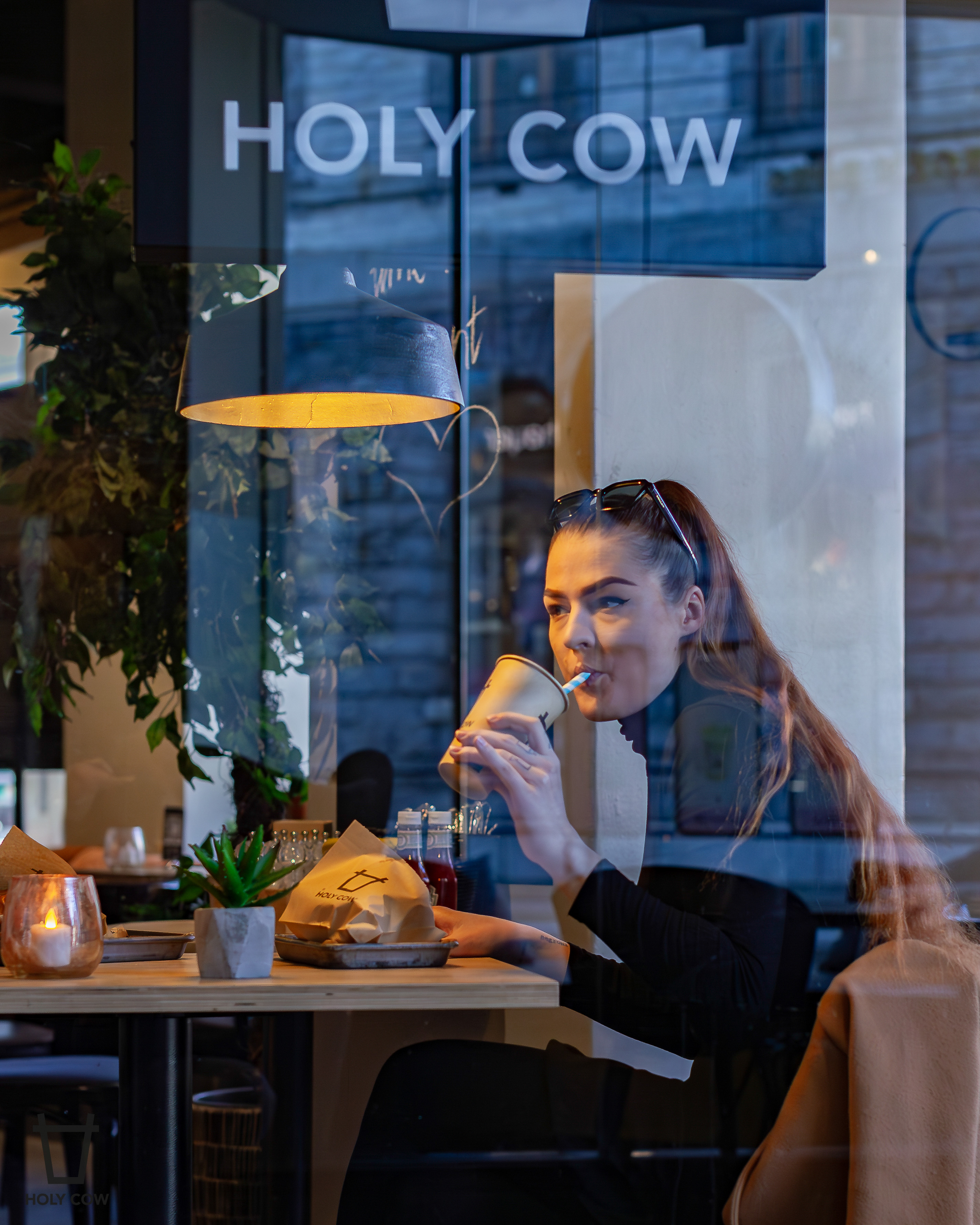 Gjest nyter drikke ved et bord på Holy Cow burgerrestaurant i Galleriet, Bergen